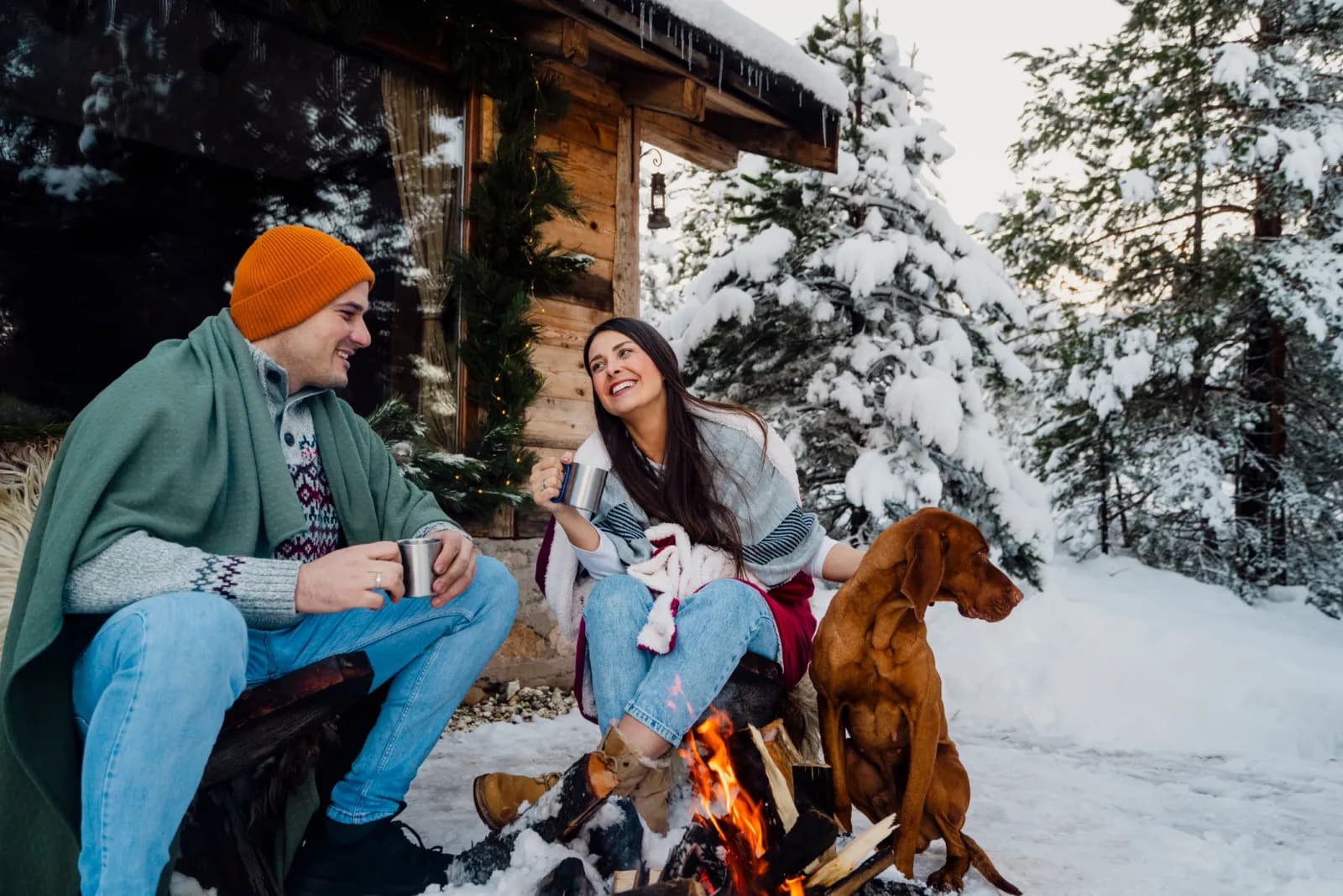 Guests warming up by the fire pit at a snowy cabin